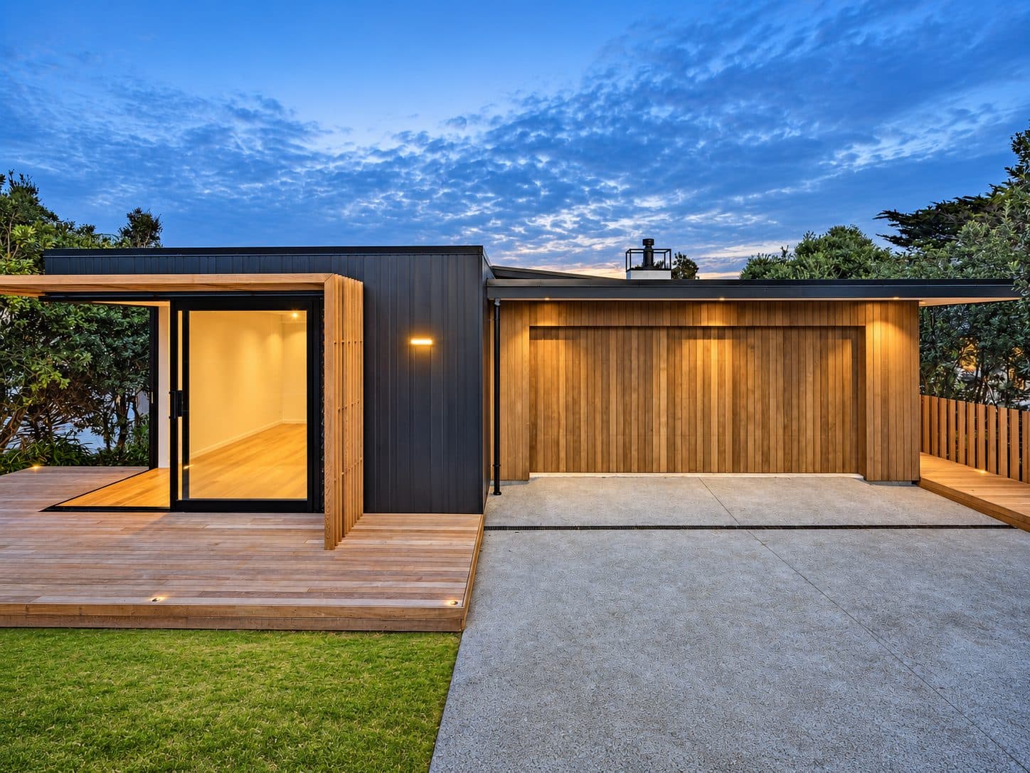 A cedar-clad home at dusk with a matching timber garage door