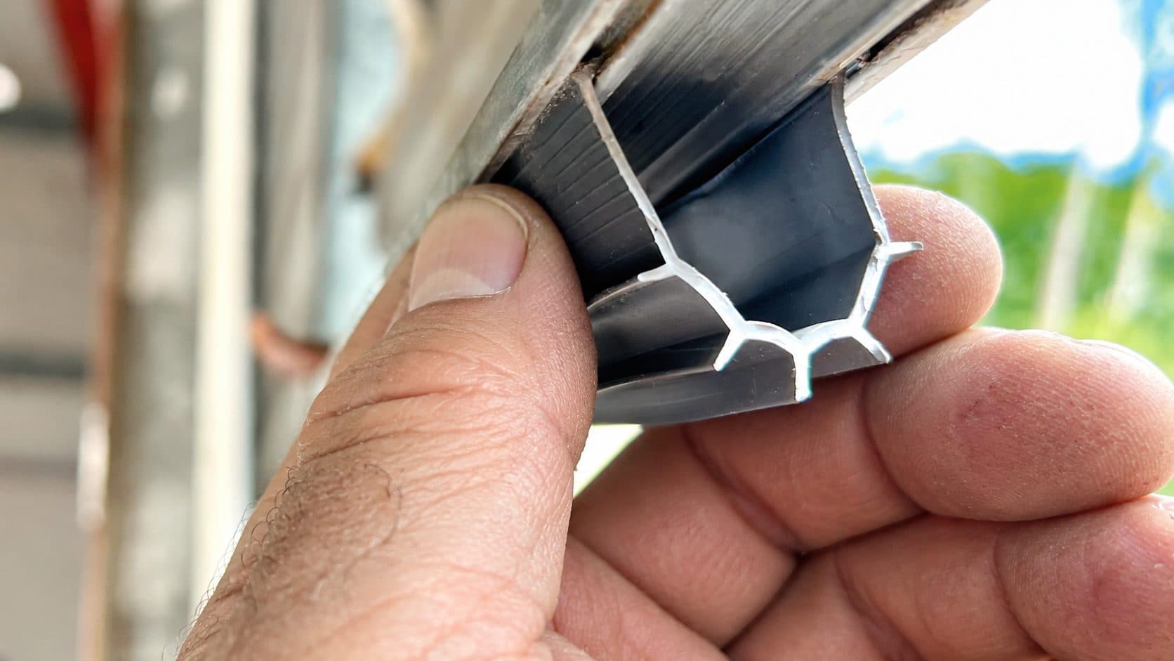 A hand holding an aluminium seal carrier with the rubber in it
