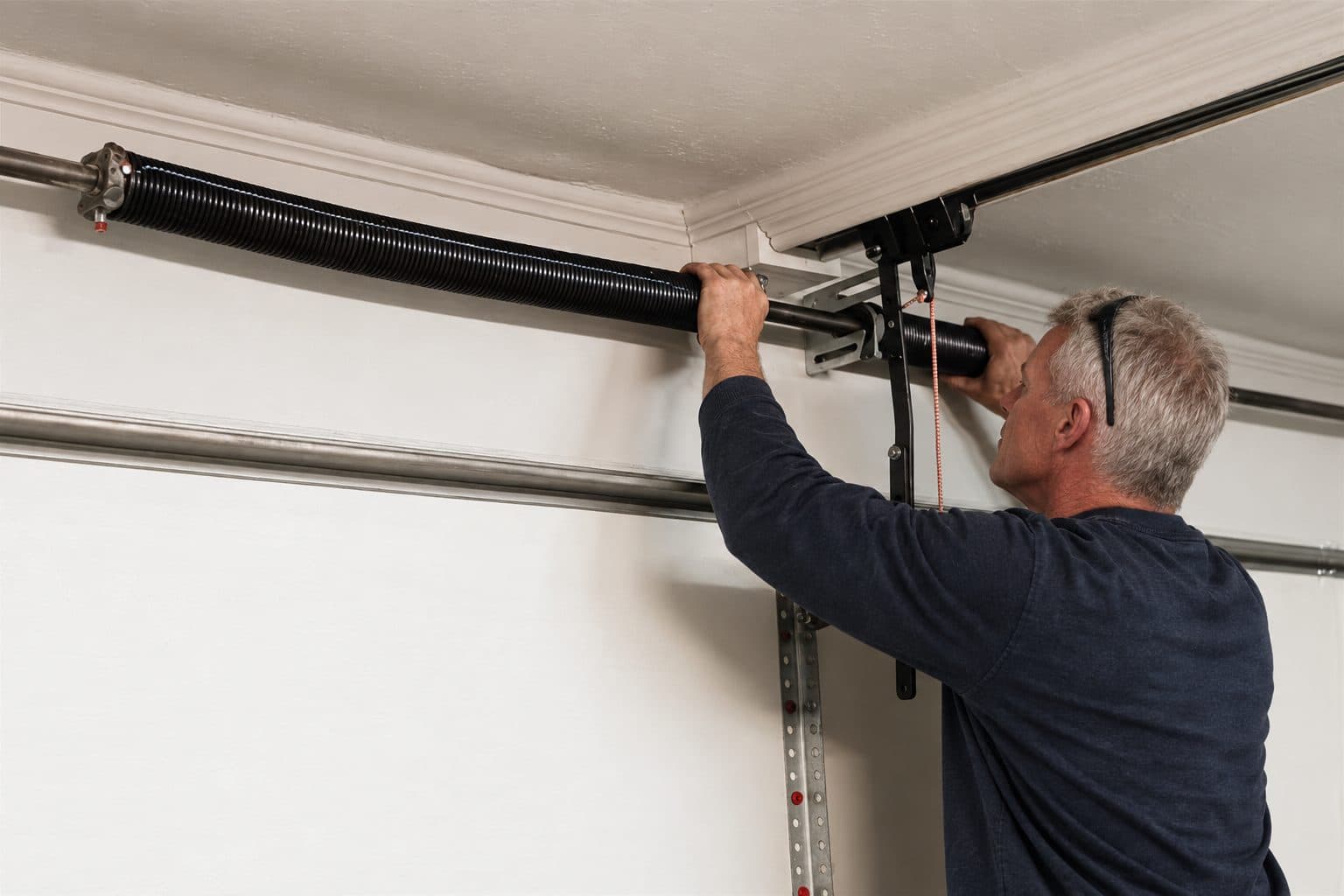 A technician re-tensioning a torsion spring above a garage door